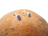 Pair of silver earrings with colorful stones on a brown stone surface
